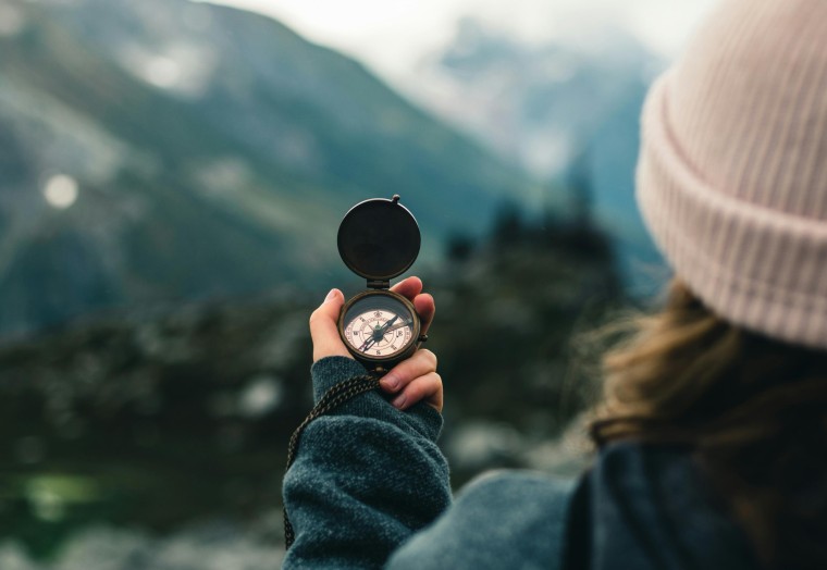 Woman hiking, holding a compass in her hand
