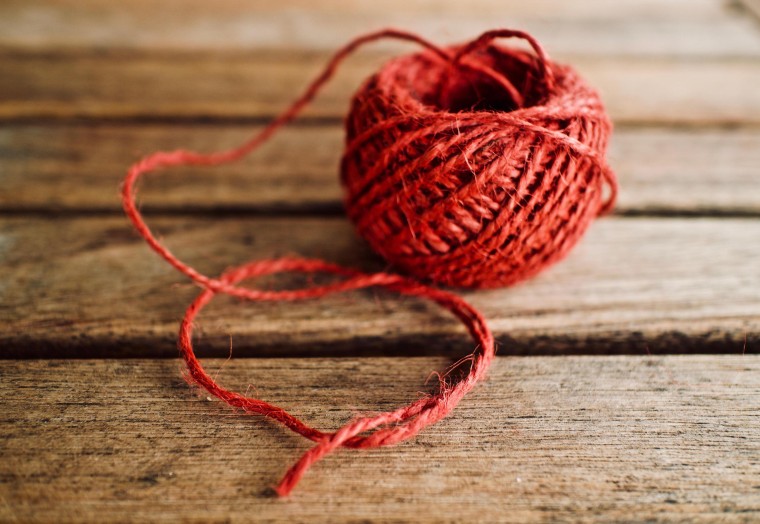Ball of red string on a wooden floor