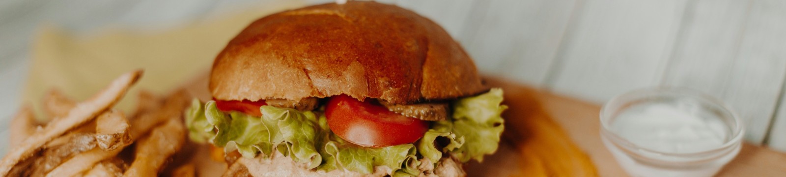 tasty burger on a board with chips and sour cream on the side