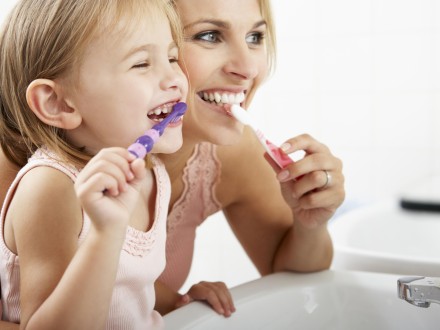 mother and child brushing teeth and smiling