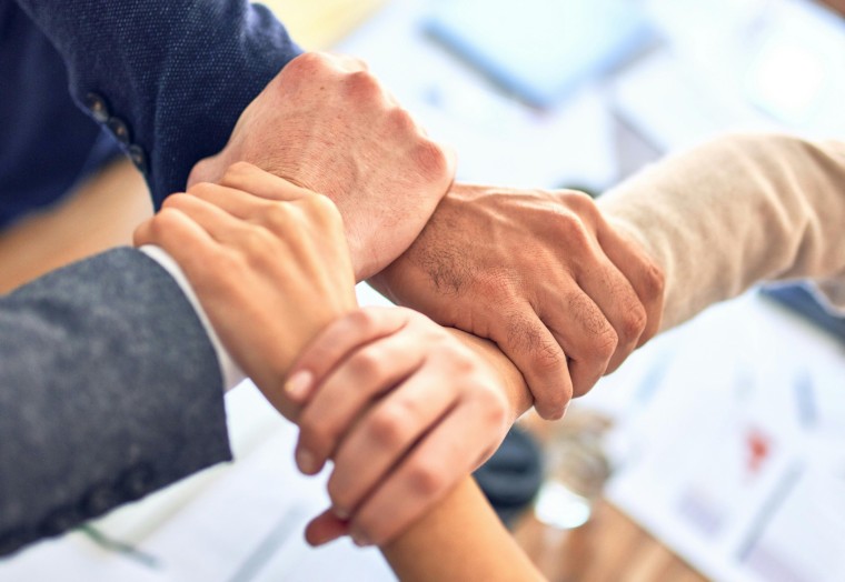 Four hands holding each other in a circle
